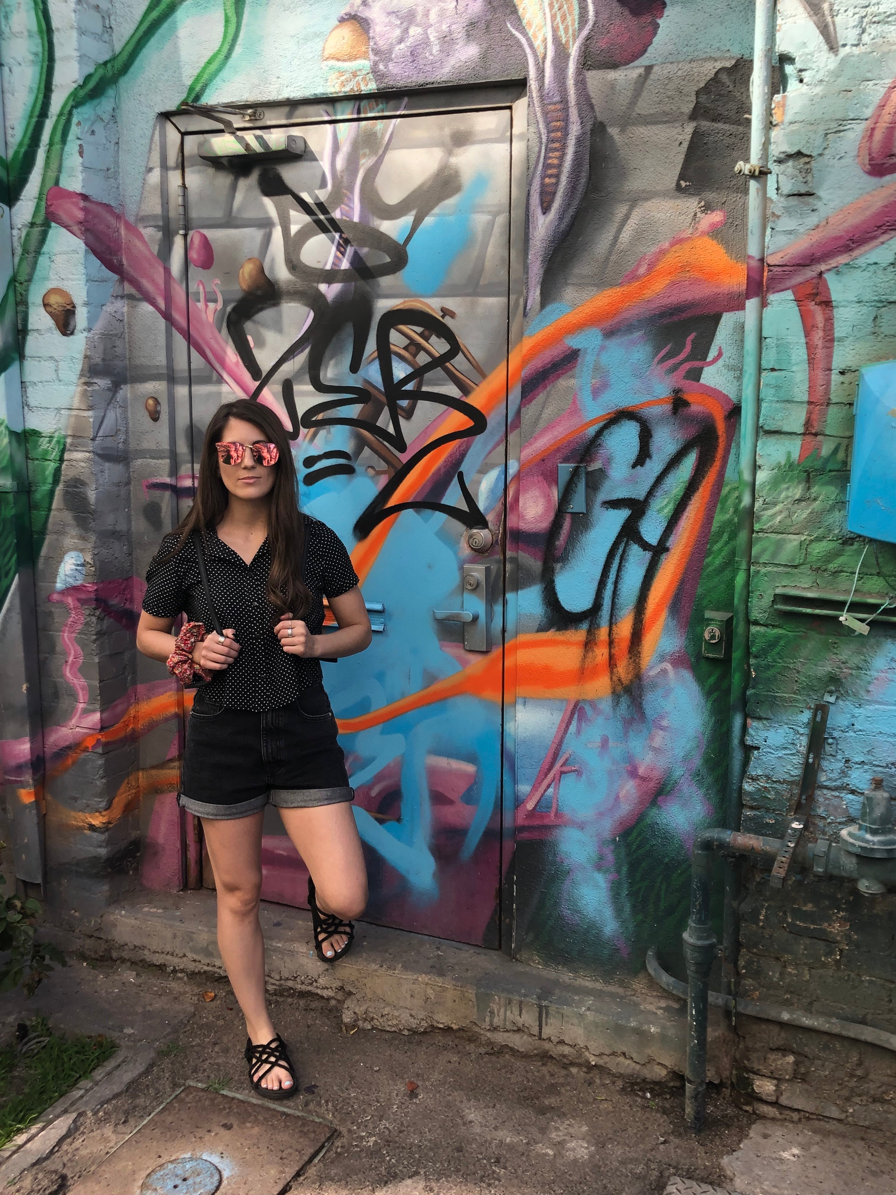 modeling in sandals beside a graffiti wall